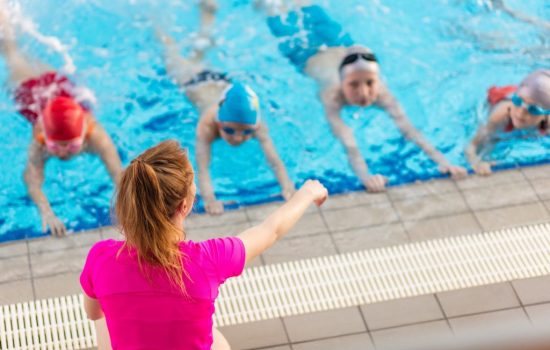 happy children kids group at swimming pool class learning to swim